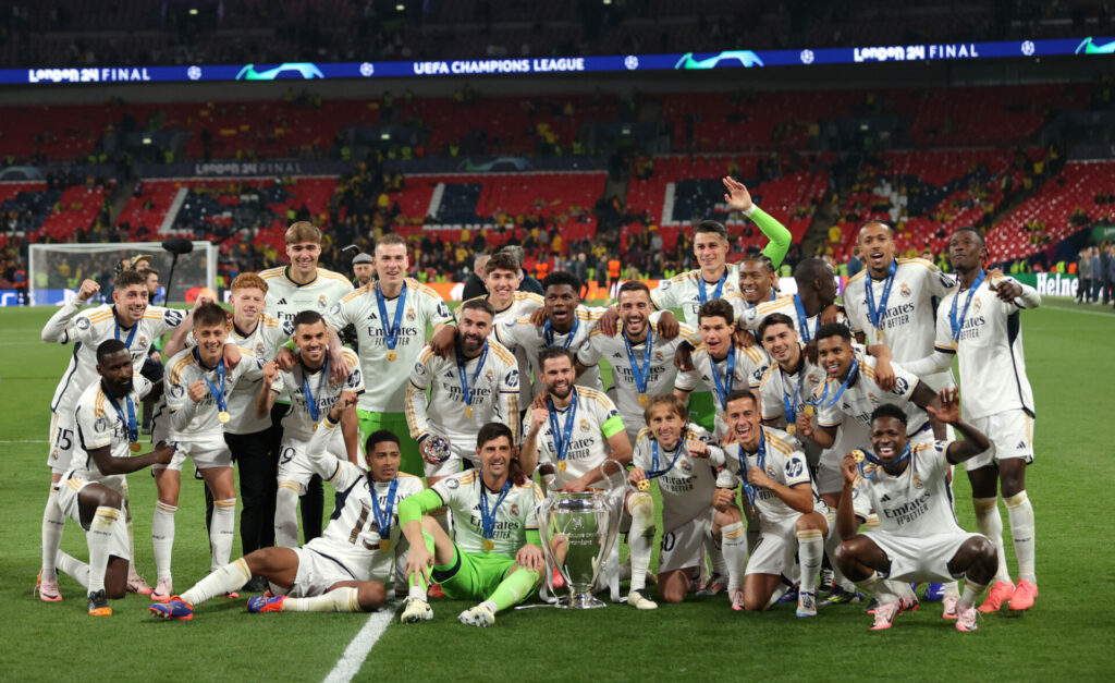 La plantilla del Real Madrid posa con el trofeo de campeones de la Champions League en el césped de Wembley.