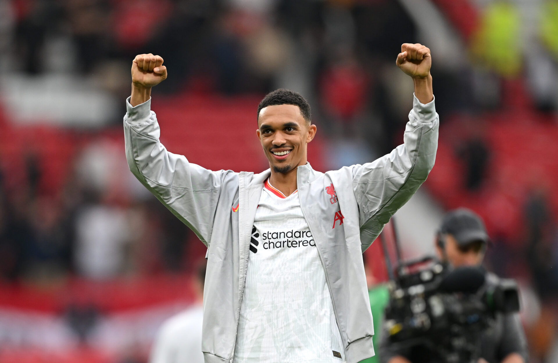 Alexander-Arnold levanta los brazos con la camiseta blanca del Liverpool.