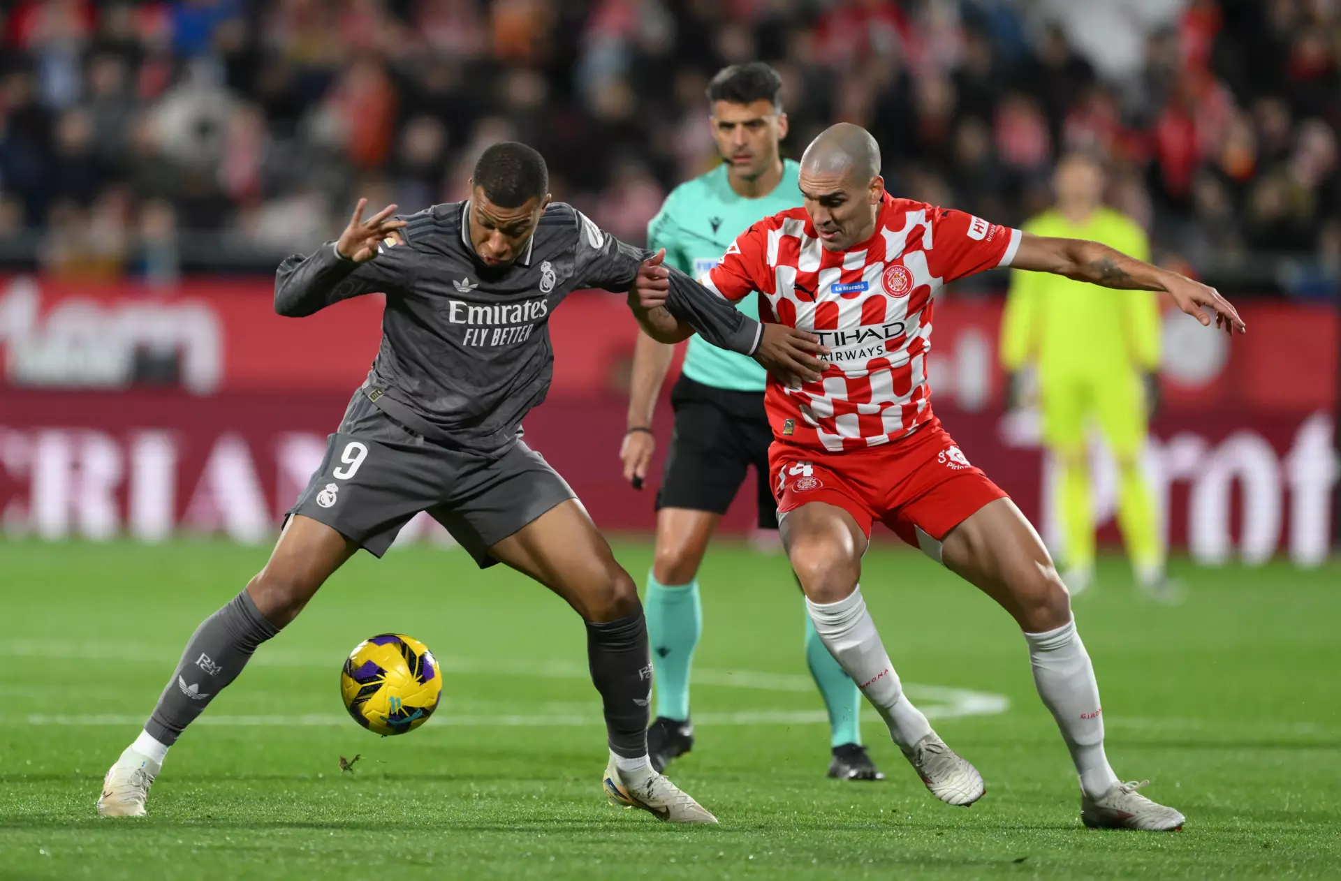 Mbappé, del Real Madrid, y Oriol Romeu, del Girona, pelean por un balón.