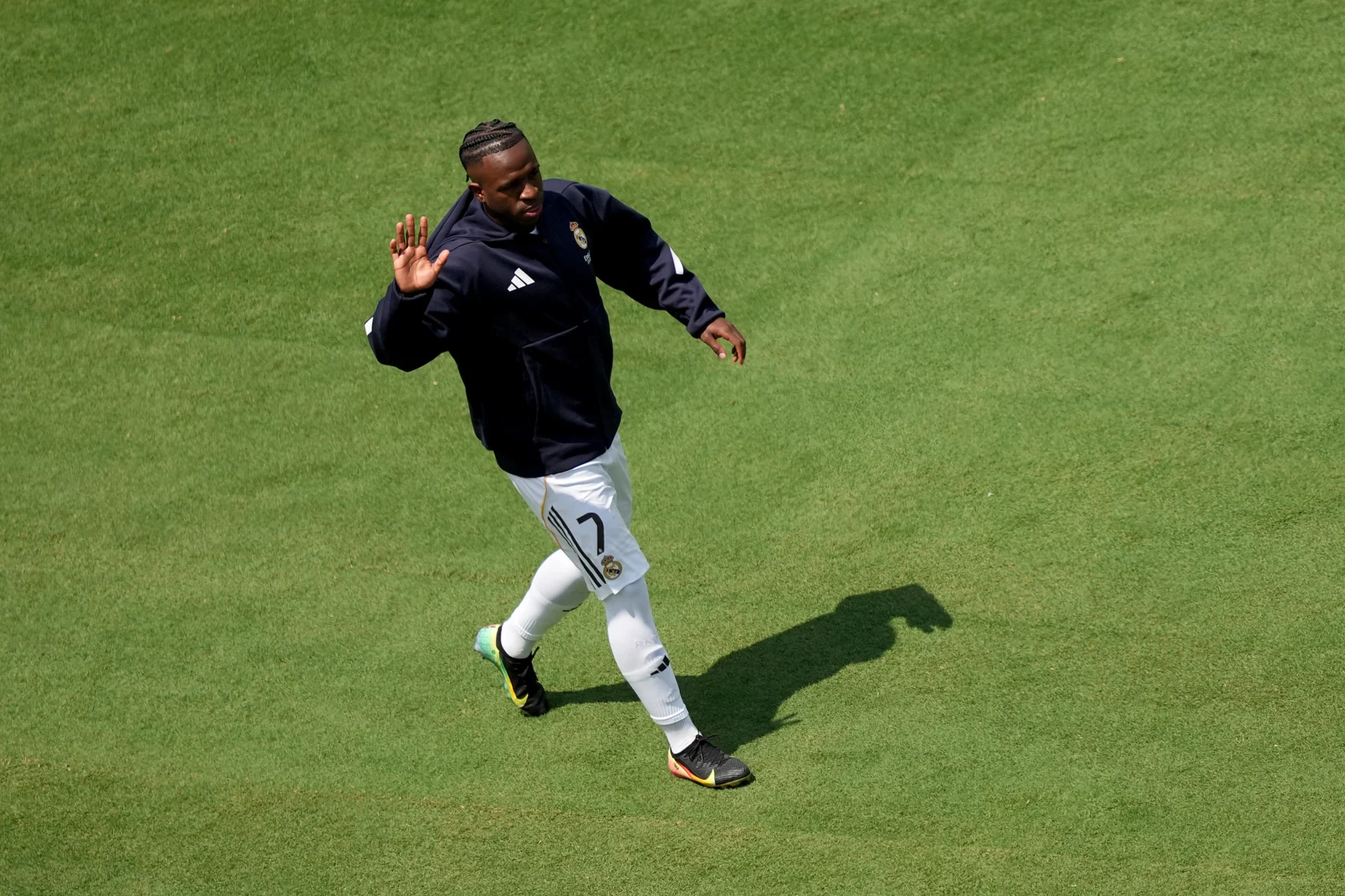 Vinicius pone fin a las especulaciones Vinicius levanta la mano derecha entrando al césped con el Real Madrid