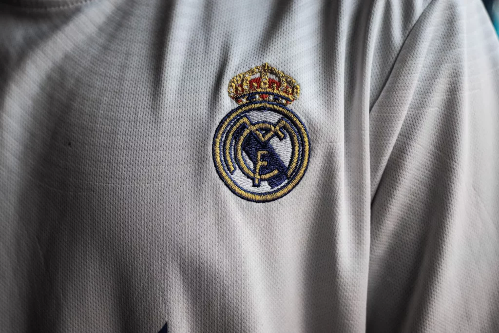 El escudo del Real Madrid bordado sobre una camiseta blanca.