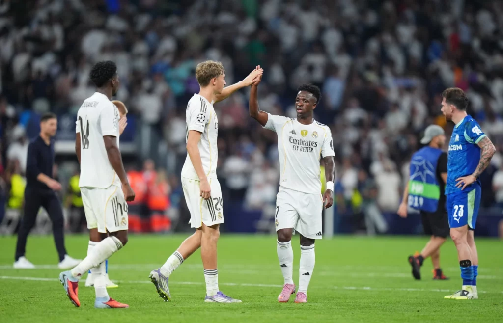 Vinicius Junior, con rostro serio, se saluda con Dean Huijsen tras un partido del Real Madrid en el Santiago Bernabéu