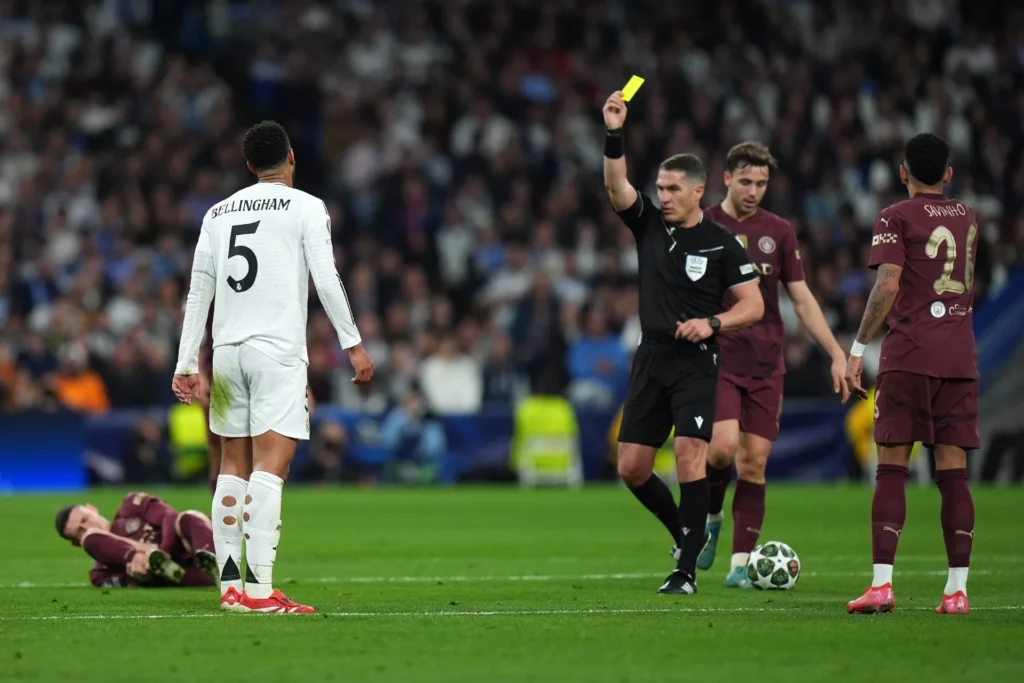 El árbitro István Kovács muestra una tarjeta amarilla a Jude Bellingham del Real Madrid.