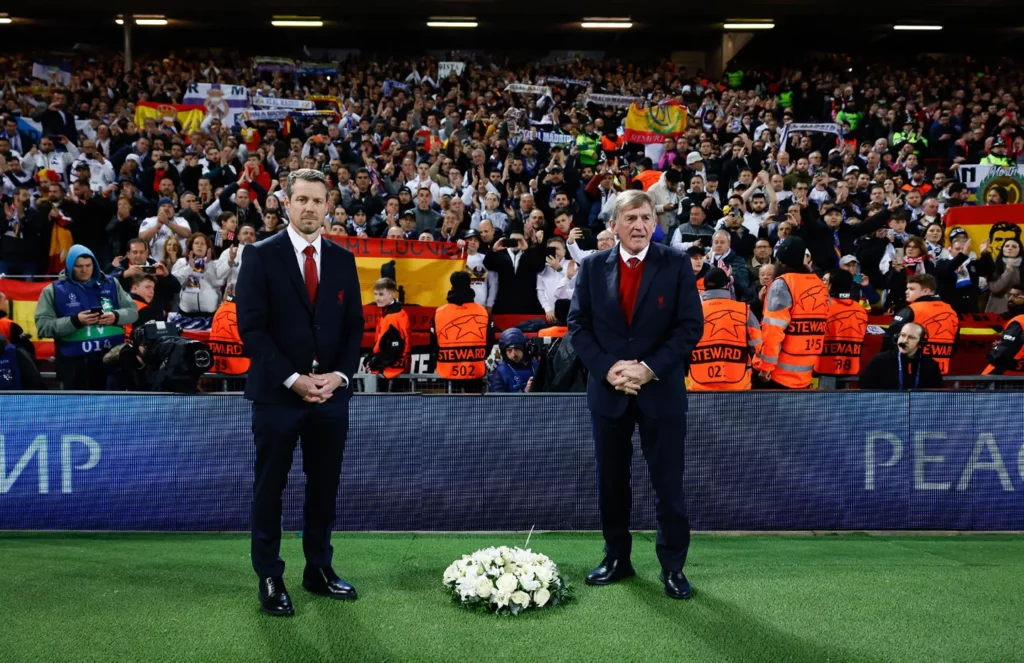 Representantes del Liverpool colocan una corona de flores en recuerdo a Amancio Amaro frente a la afición del Real Madrid en Anfield