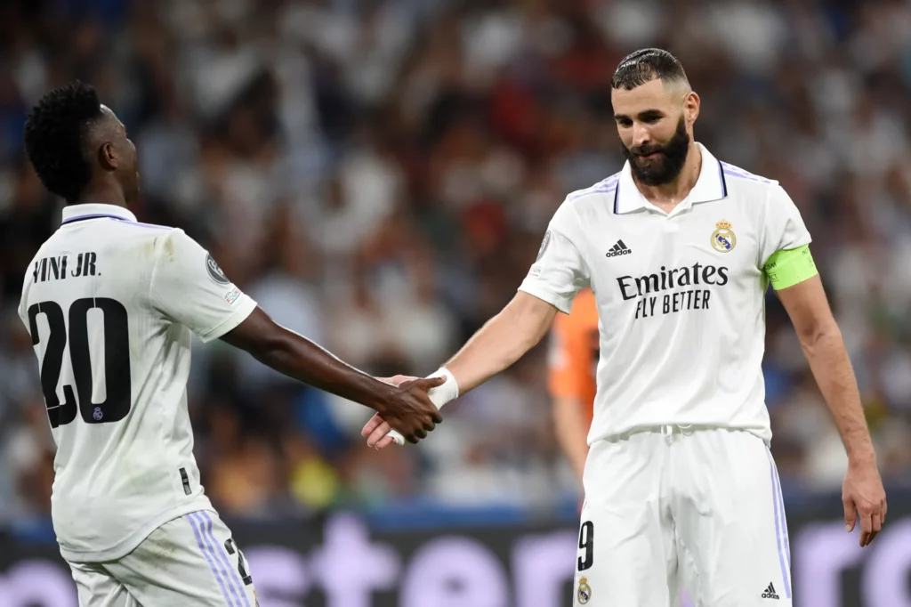 Benzema se saluda con Vinicius durante un partido del Real Madrid en el Santiago Bernabéu.