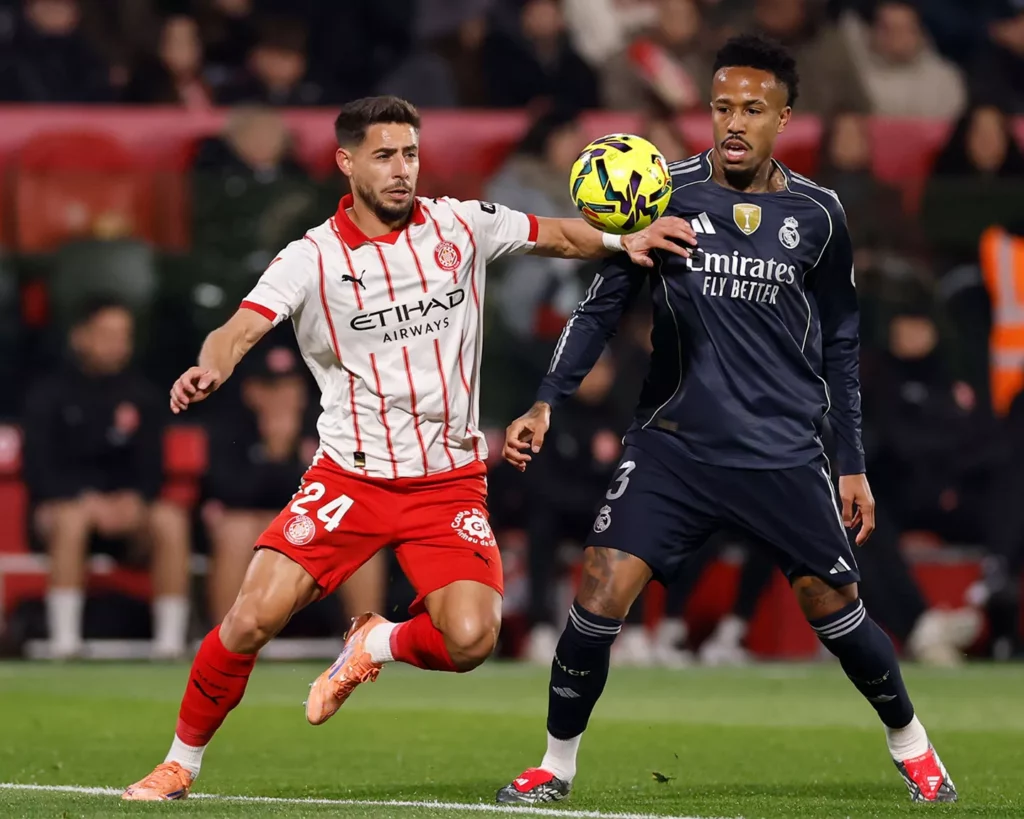 Militao y Álex Moreno pelean por el balón en Montilivi durante el Girona - Real Madrid.