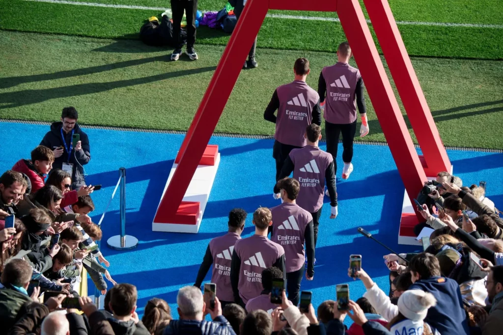 Los jugadores del Real Madrid saltan al césped rodeados de la afición en las gradas.