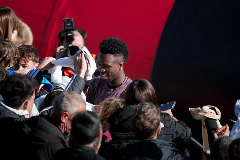 Vinicius firma autógrafos a la afición del Real Madrid presente en el entrenamiento a puerta abierta.