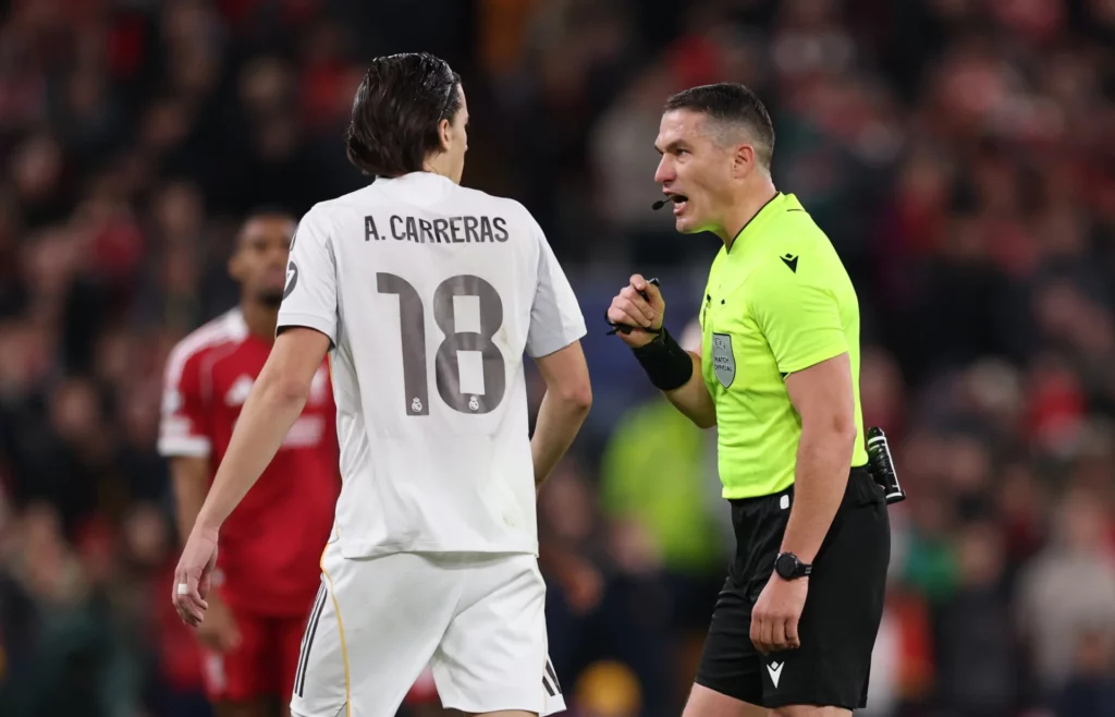 Álvaro Carreras recibe la reprimenda del árbitro durante un partido de Champions contra el Liverpool.