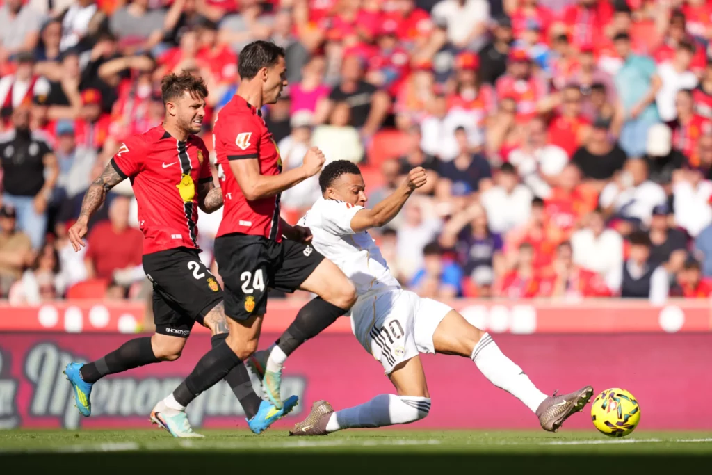 Kylian Mbappé remata forzando en Son Moix ante el marcaje de los defensores del RCD Mallorca.