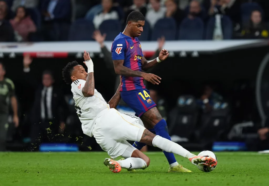Militao realiza una entrada sobre Rashford durante un partido entre Real Madrid y Barcelona en el Santiago Bernabéu.