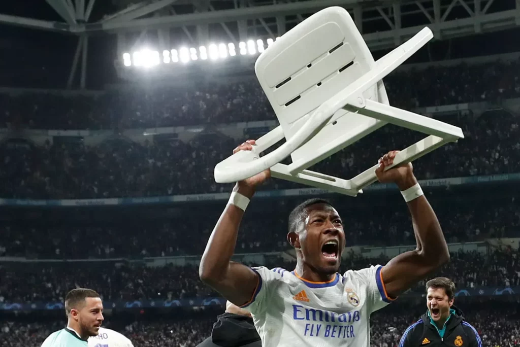 David Alaba celebra uno de los goles del Real Madrid al PSG en 2022 levantando una silla.
