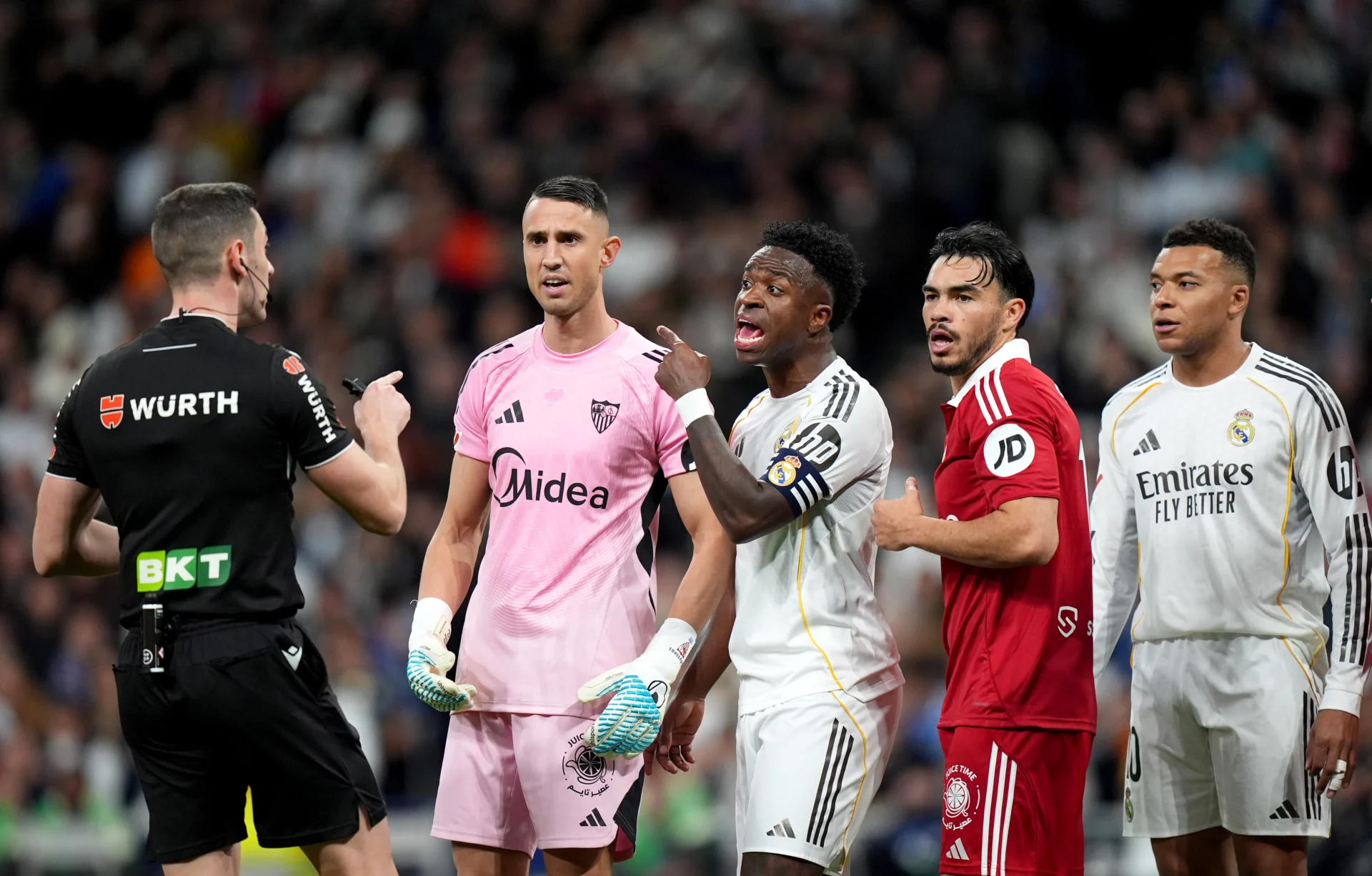 Vinicius, Vlachodimos, Mbappé y Suazo protestan al árbitro durante un partido entre Real Madrid y Sevilla FC.