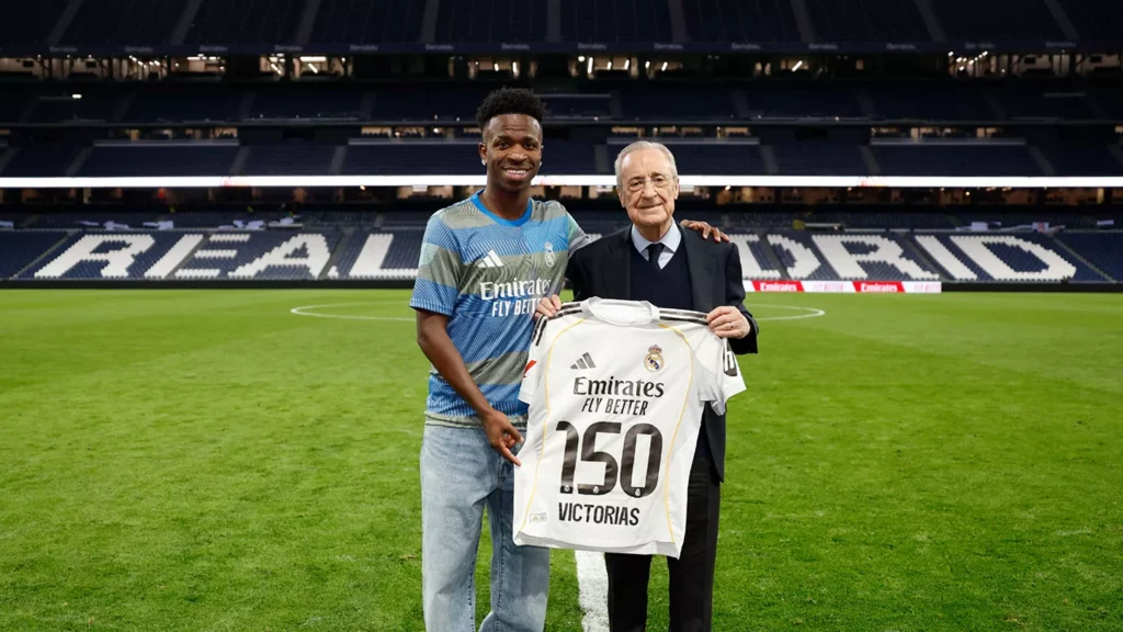 Vinicius y Florentino Pérez posan con una camiseta del Real Madrid en el Santiago Bernabéu.